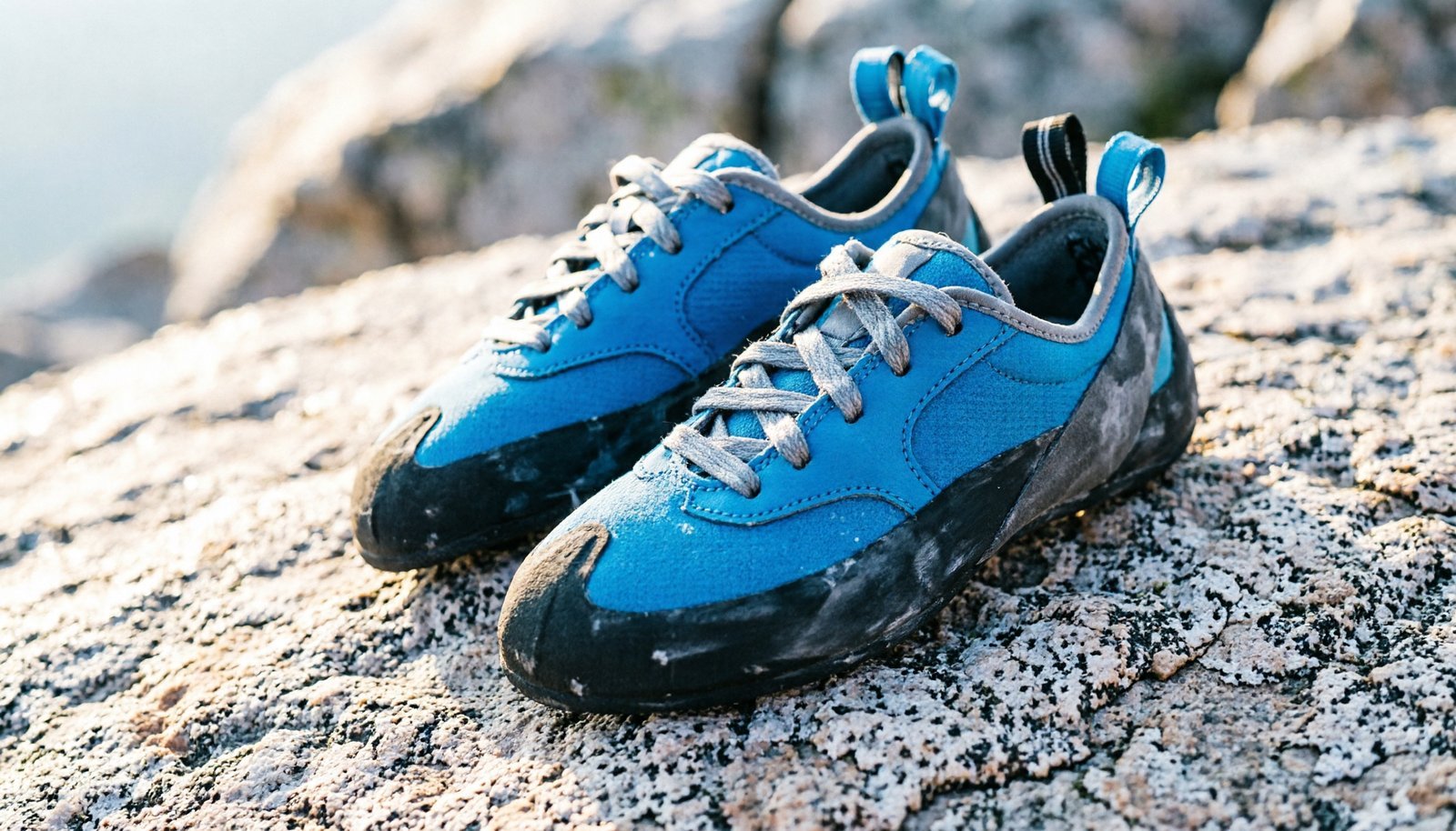 Pair of professional climbing shoes resting on a textured granite rock surface.